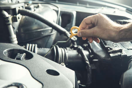 Mechanic checking the motor oil level in the car engineの写真素材