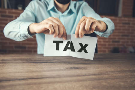 Angry businessman tearing a tax in officeの写真素材