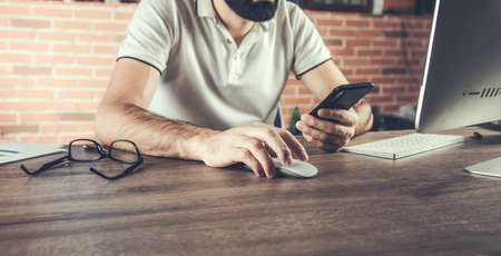 young man working from office using smart phone and computerの写真素材