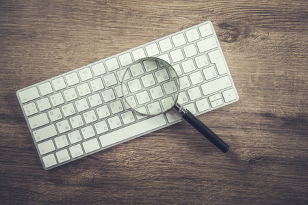 magnifier on the white keyboard on wooden backgroundの写真素材