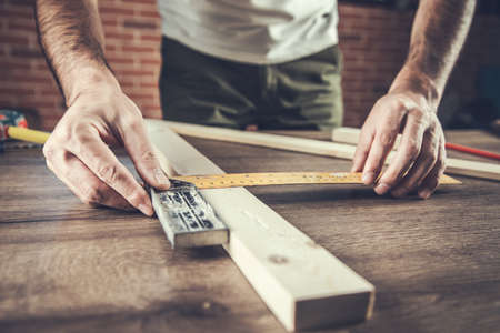 the man carpenter measures the wooden board