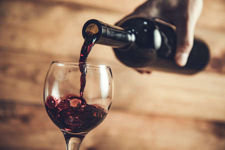 pouring grape wine into a glass on the tableの写真素材