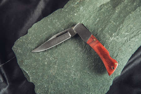 the pocket knife on the stone background