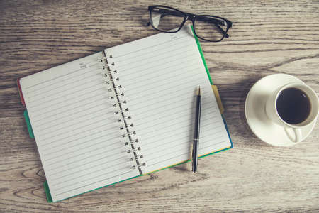 notepad and glasses with coffee on the tableの写真素材