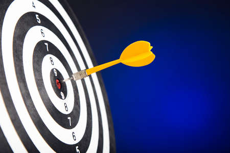 Darts arrows in the target center on blue backgroundの写真素材