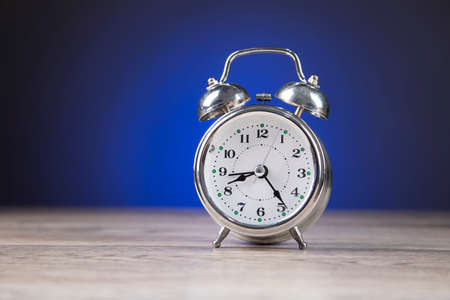 clock on wooden desk and on blue background