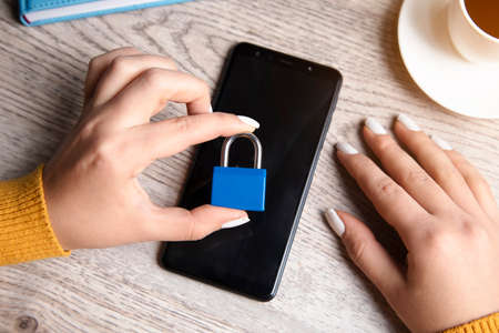 woman holding lock on phone on tableの写真素材