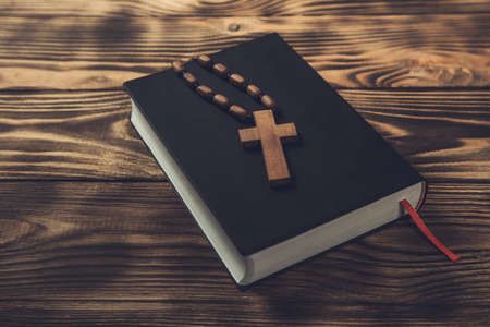 wooden cross on Holy Bible on wooden background