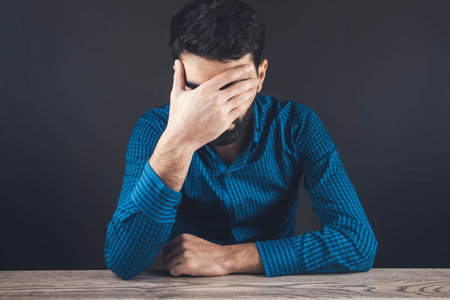 sad young man sitting on the tableの写真素材