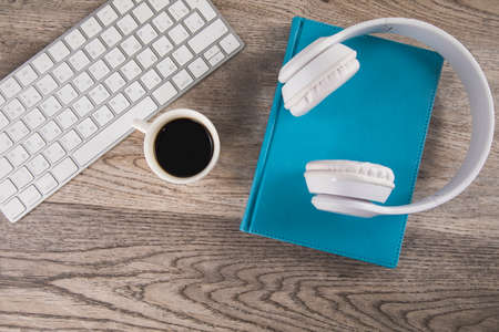 earphone on book with keyboard and coffee on table