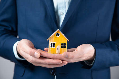 business man holding wooden house modelの写真素材