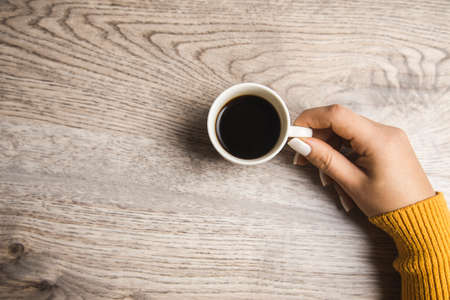 woman holding cup of coffee on tableの写真素材