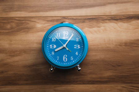 blue clock on the wooden table backgroundの写真素材