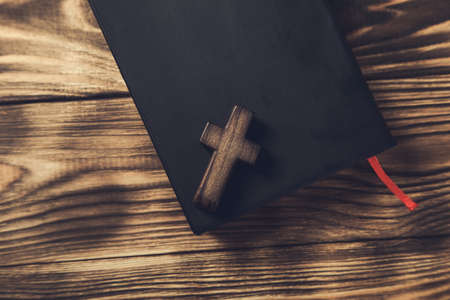 wooden cross on Holy Bible on wooden background