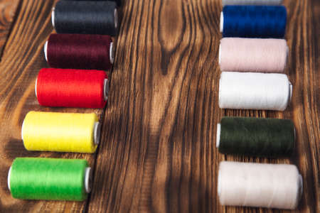 colorful thread spools on the wooden background.