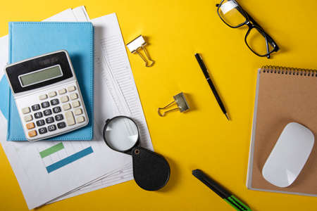 calculator with notebook and computer mouse and magnifier on table