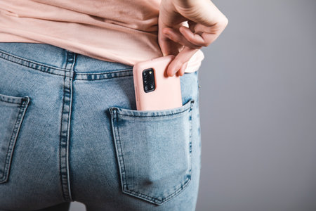 woman holding smart phone in jeans pocket