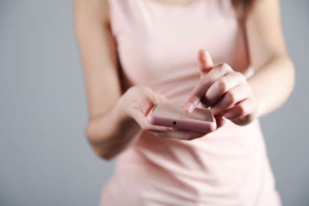 young woman holding pink smart phoneの写真素材