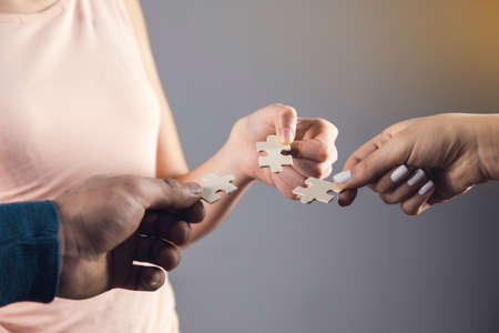 a group of people holding puzzle together.の写真素材