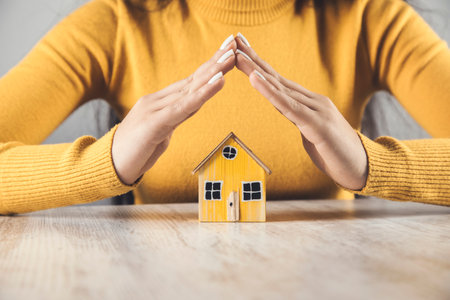 woman holding yellow house model on wooden tableの写真素材