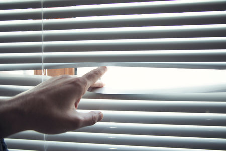 Young man opening window white blindsの写真素材