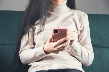 young woman using smartphone sitting on sofaの写真素材