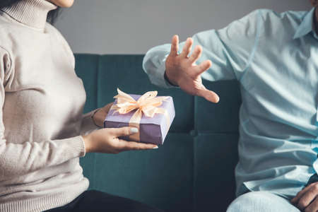 woman holding present and sad man hand no signの写真素材