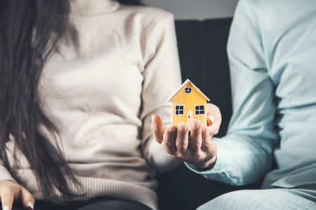 woman and man holding house model sitting on sofaの写真素材
