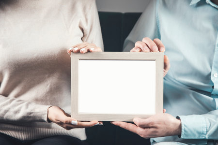 couple holding frame photo sitting on sofaの写真素材