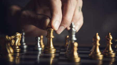 business man playing chess isolated on blackの写真素材