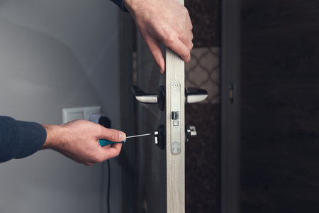 man repairing door handle with a screwdriver.の写真素材