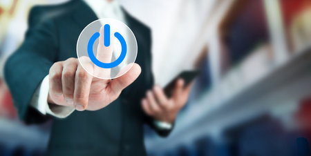 Businessman holding phone with power button.の写真素材