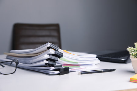 Stack of business paper file with laptop computer on desk