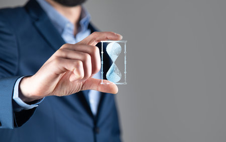 Man holds in hand hourglasses icon. time expires.の写真素材