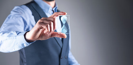 Man holds in hand hourglasses icon. time expires.の写真素材