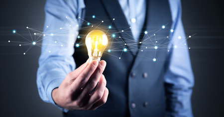 Hand of businessman holding illuminated light bulbの写真素材