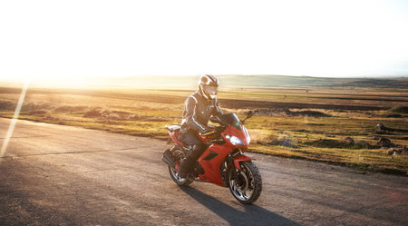 man on a motorcycle in asphalt road at the sunset
