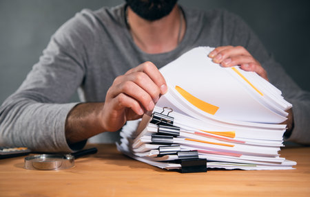 man hand stack of paper and magnifier on tableの写真素材