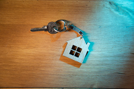 House key on house shaped key chain on wooden backgroundの写真素材