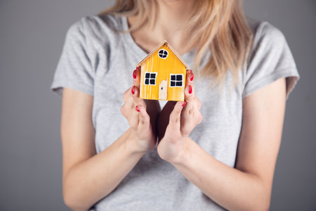 real estate, woman holding wooden house modelの写真素材
