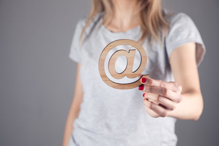 young woman holding wooden email sign on gray backgroundの写真素材
