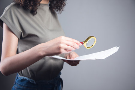 young woman holding magnifier and documentの写真素材