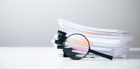 Stack of report paper documents with magnifying glass. Concept of business and search.の写真素材