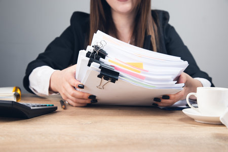 woman holding stack of business documents on tableの写真素材