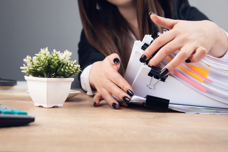 woman holding stack of business documents on table