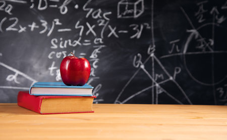 The apple on book with blackboard background.