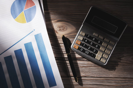 Statistical graphs and calculator with pen on table