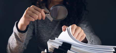 business woman holding magnifying glass and documents