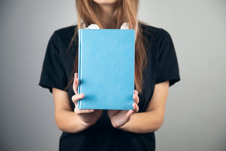 young woman reading book with earphoneの写真素材