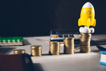 Start concept, rocket with coins on table